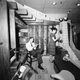 A family room designed to serve also as a fallout shelter is occupied, for demonstration purposes, by Thomas Wilson, reading, and Elise Paul, opening a can. The room is on view at the National Design Center in New York, Feb. 3, 1960 in a cutaway version to show its concrete block walls and ceiling jousts. (AP Photo/Dan Grossi)